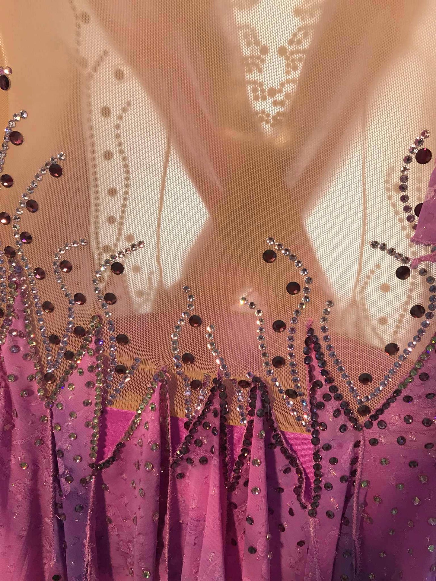 Crystal's Creations close up of backview of Orchid ballroom dress created in yards of a textured chiffon in shades of orchids & purples on a nude illusion base with floats & Swarovski stonework in gorgeous shades of orchids & purples.