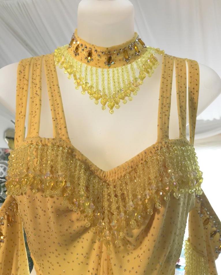 Top detail view of Crystal's Creations Yellow Latin/rhythm dress created of yellow glitter slinky features hand beaded fringe, cut out midriff sides, CAB Swarovski rhinestone work & a touch of turkey feathers.