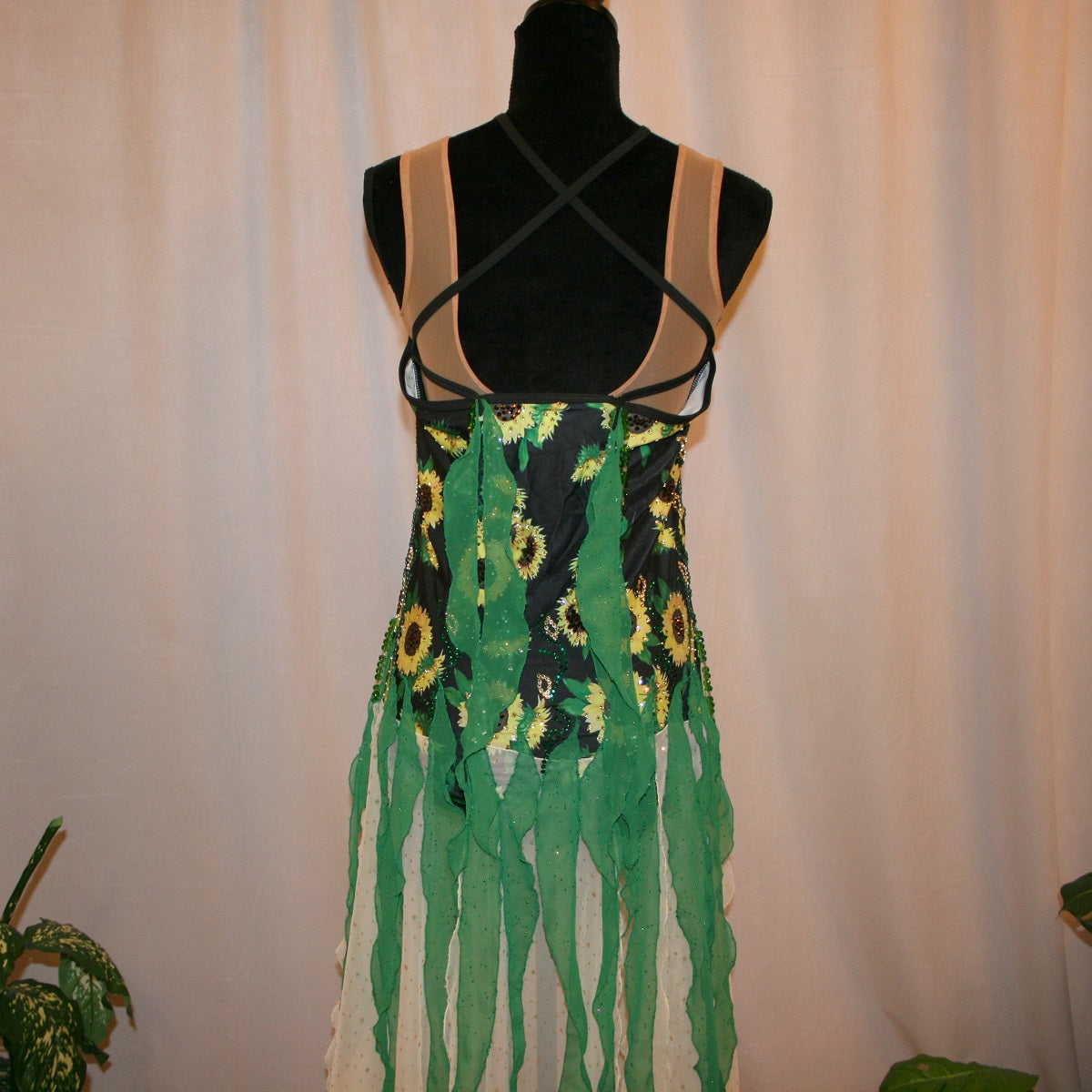 Upper back view of all around ballroom dress that features yards of gorgeous soft yellow champagne sequin chiffon hand cut in large petal shapes for the skirting that is short in front & cascades longer in the back. Overlays of emerald flocked green chiffon skillfully hand crafted creating thin leaf shapes. Flows so beautifully for your foxtrots & waltzes! Lots of sparkle comes from the detailed rhinestone work