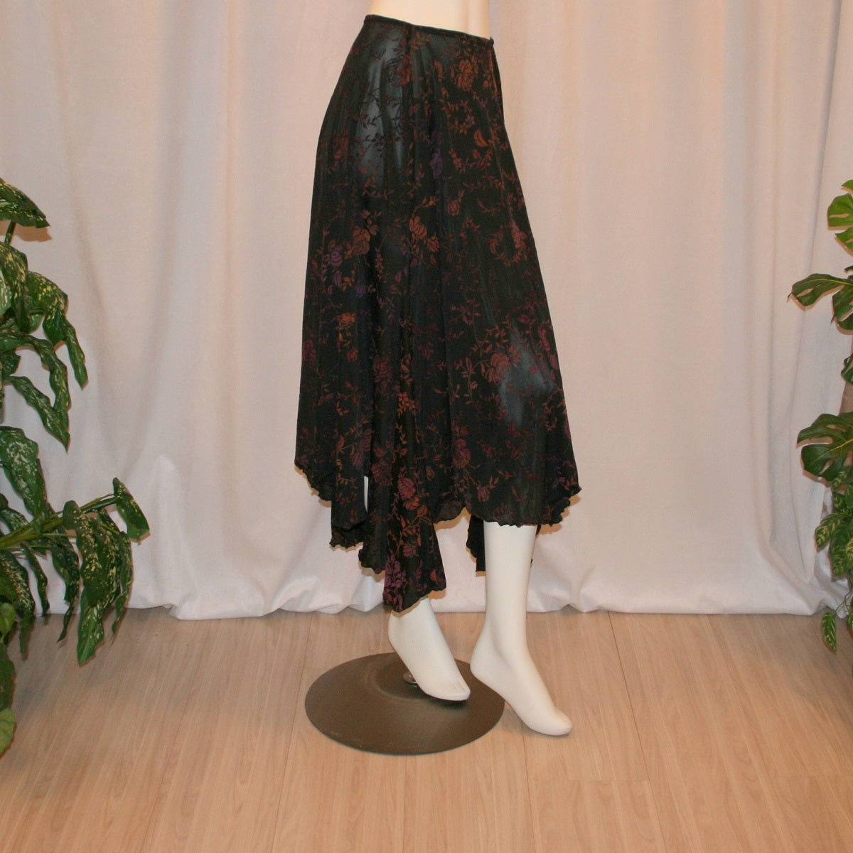 right side view of Black velveteen ballroom skirt with a gorgeous floral pattern, it creates a delightful swirl of autumn colors with its gored seaming and abundant fullness, and elasticized waist for ease of fit. Deep scalloped hemline adds a touch of charm, perfect for any ballroom event, studio dance parties, practice, or teaching!