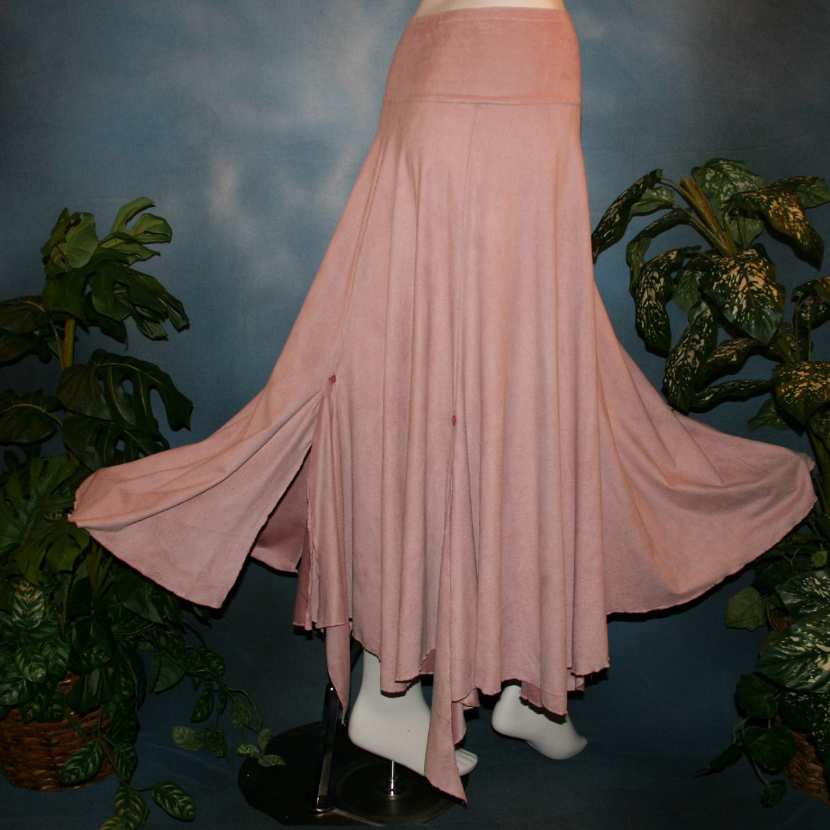 side flared view of Lovely light rose dance skirt created of slightly stretchable suede cloth featuring a wide waist sash that flares out to several panels, with slits that have smaller floating panels with a rose colored acrylic gem at each.