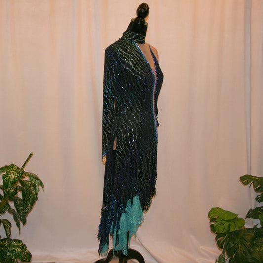 right side view of black Latin-rhythm dress sparkles plenty on the dance floor with a stunning black glitter fabric featuring a wavy turquoise, aqua & royal blue design, complete with black hand-beading, aqua teardrop shape beads, spangles, and intricate flounces in various fabrics of deep shimmering blue, turquoise, aqua & black.