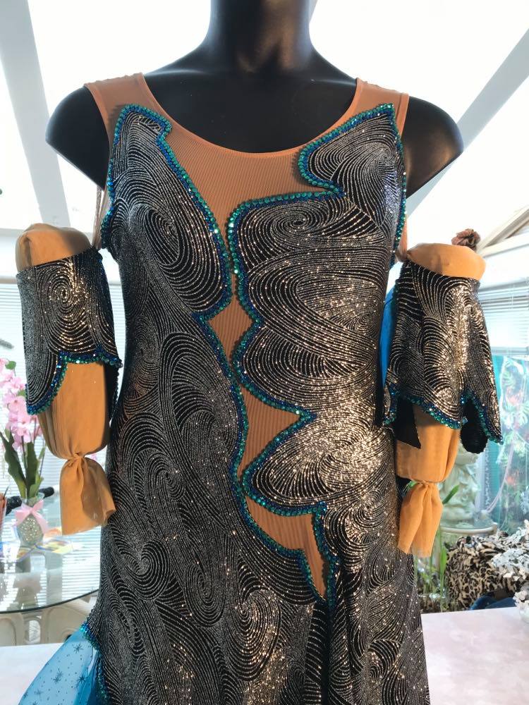 Crystal's Creations close up view of Gorgeous silver ballroom dress, designed to be fabulous for a solo ballroom dance, bolero, rumba or tango, was created on a nude illusion base of silver swirls glitter slinky fabric intricately cut & placed. Then flounces of deep turquoise sea blues size 9/10-11/12, possibly 13/14