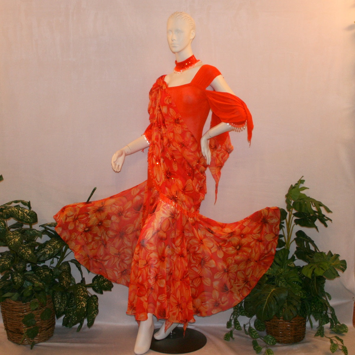 left side view of Orange ballroom dress with 3/4 cold shoulder, billowy sleeves, created of luxurious orange solid slinky & yards of an orange tropical print textured chiffon.