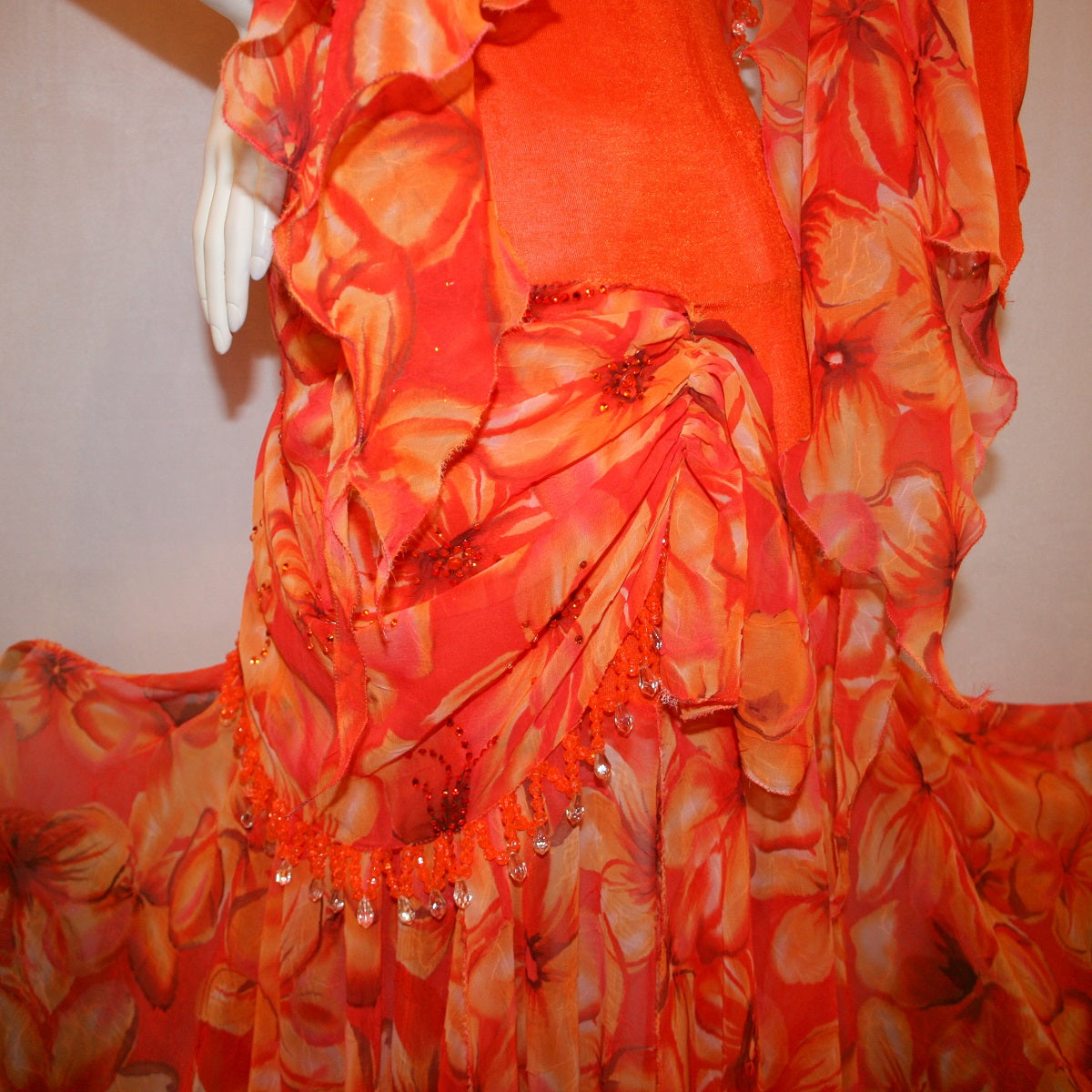 close side view of Orange ballroom dress with 3/4 cold shoulder, billowy sleeves, created of luxurious orange solid slinky & yards of an orange tropical print textured chiffon. 