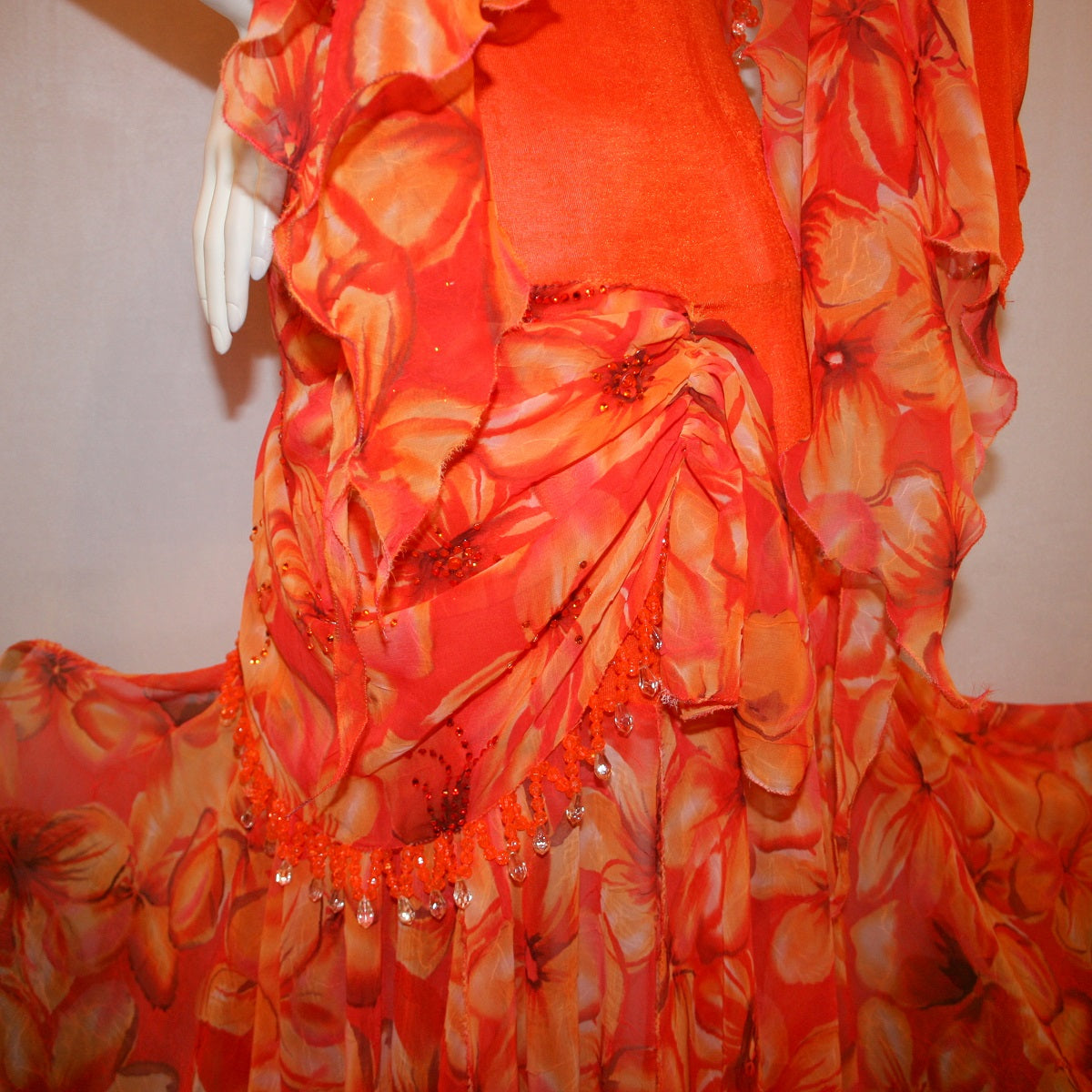 close side view of Orange ballroom dress with 3/4 cold shoulder, billowy sleeves, created of luxurious orange solid slinky & yards of an orange tropical print textured chiffon.