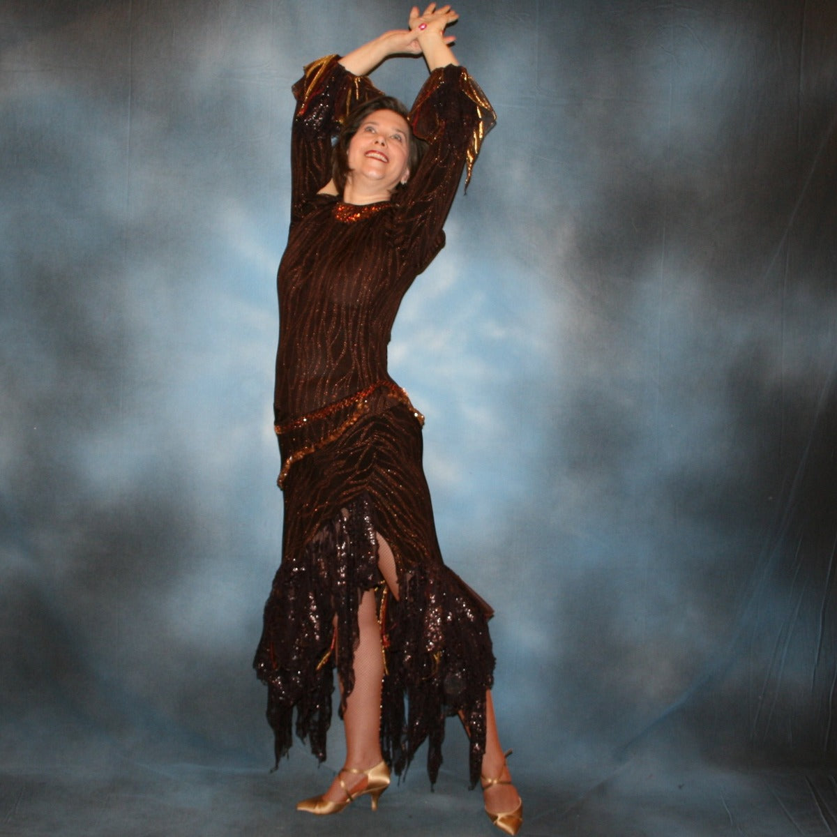 side view of Brown tango dress, bolero dress or rumba dress created in chocolate brown & bronze glitter slinky with chocolate brown metallic lace & metallic tricot flounces is embellished with crystal copper Swarovski rhinestones at neckpiece & hipsash, which also has extensive hand beading.