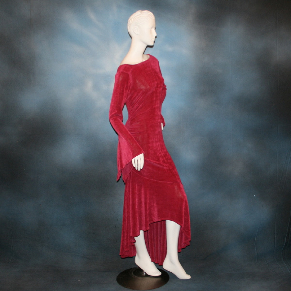 right side view of Deep rose Latin/rhythm/social dress created of luxurious deep rose slinky features ruching up the right side & long sleeves with an open flared detail.