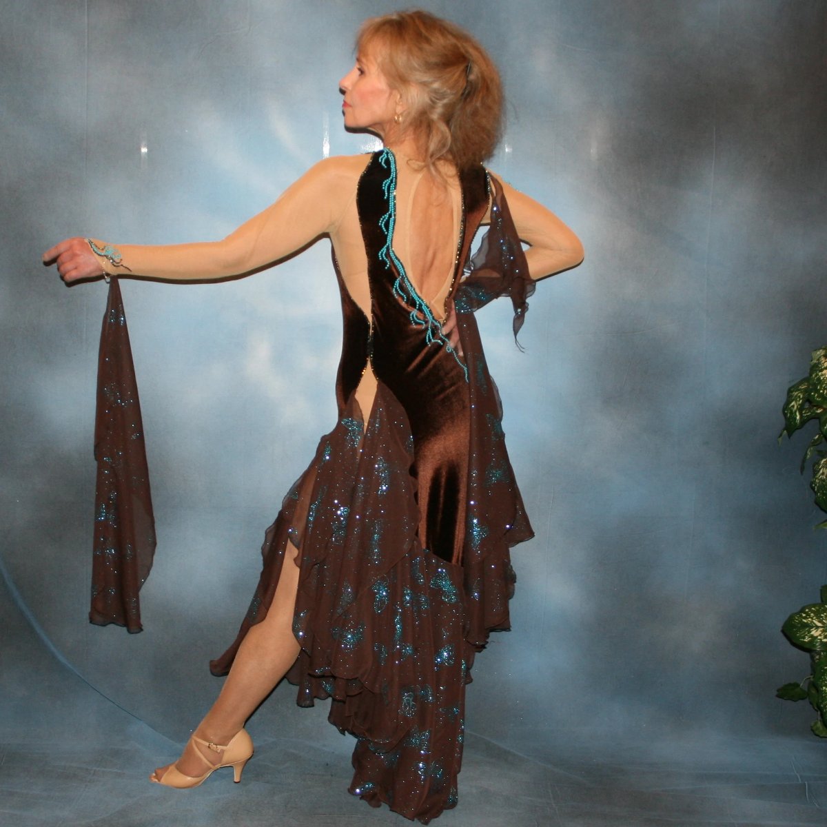 Crystal's Creations side back view of Exquisite brown ballroom dance dress with turquoise accents was created in luxurious chocolate brown stretch velvet on a nude illusion base…featuring billowing yards of brown chiffon petal panels with glittery turquoise butterflies.
