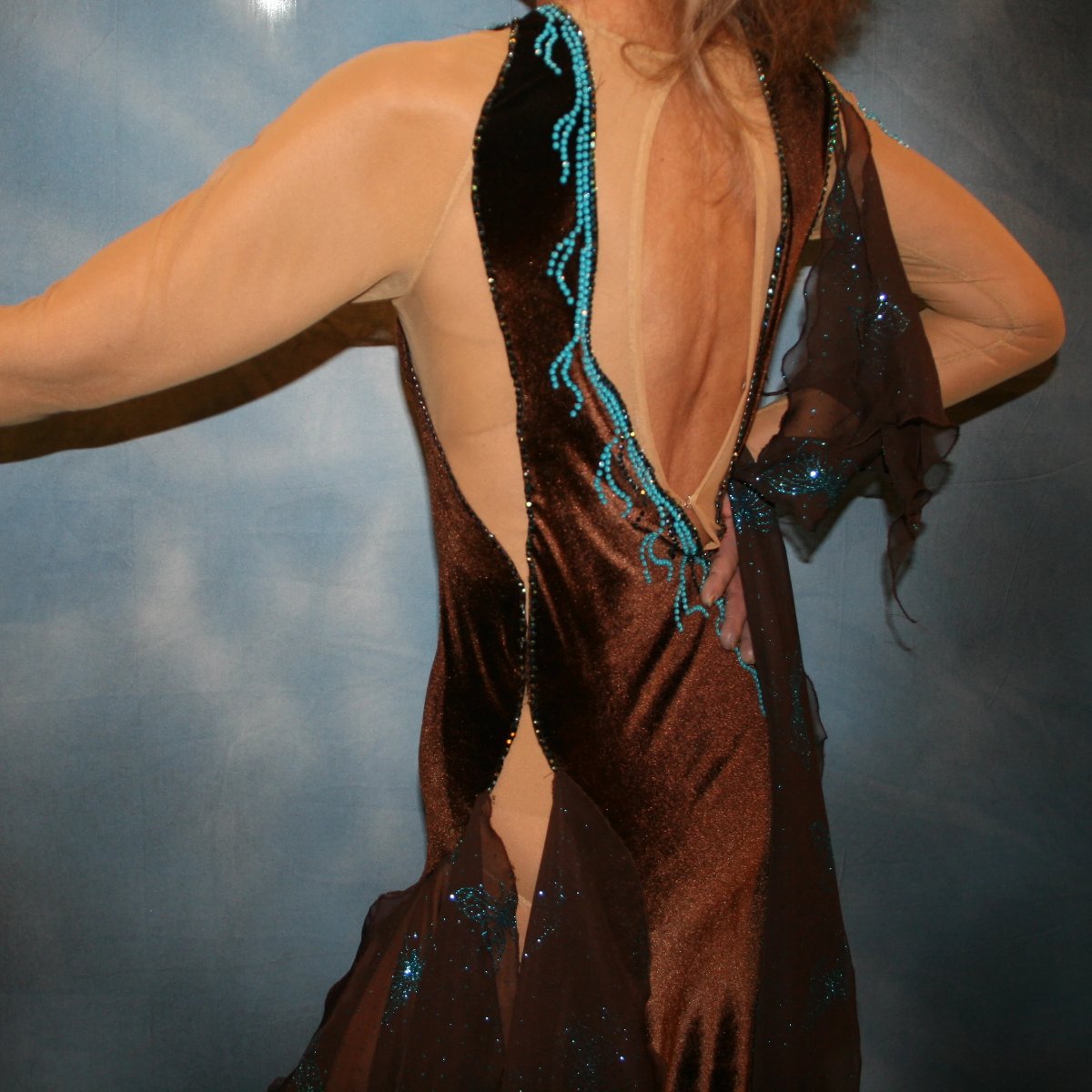 Crystal's Creations close up left back view of Exquisite brown ballroom dance dress with turquoise accents was created in luxurious chocolate brown stretch velvet on a nude illusion base…featuring billowing yards of brown chiffon petal panels with glittery turquoise butterflies.