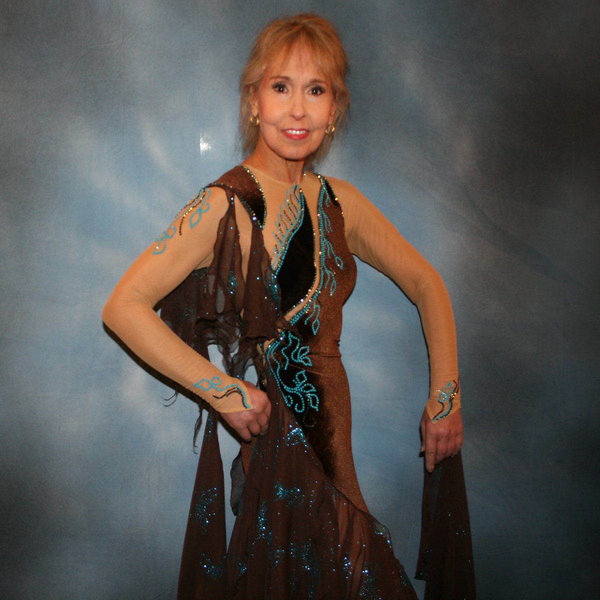 Crystal's Creations close up view of Exquisite brown ballroom dance dress with turquoise accents was created in luxurious chocolate brown stretch velvet on a nude illusion base…featuring billowing yards of brown chiffon petal panels with glittery turquoise butterflies.