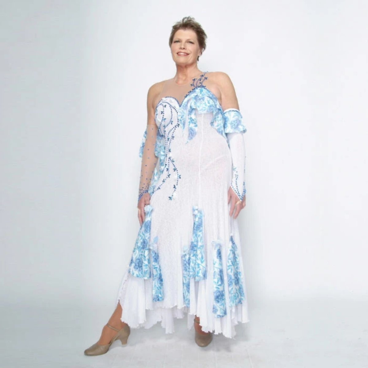 White ballroom dress with blue accents was created on nude illusion of a soft white knit with flounce accents of sky blue & white floral print satin, embellished with sapphire Swarovski stonework & miniature white silk roses.