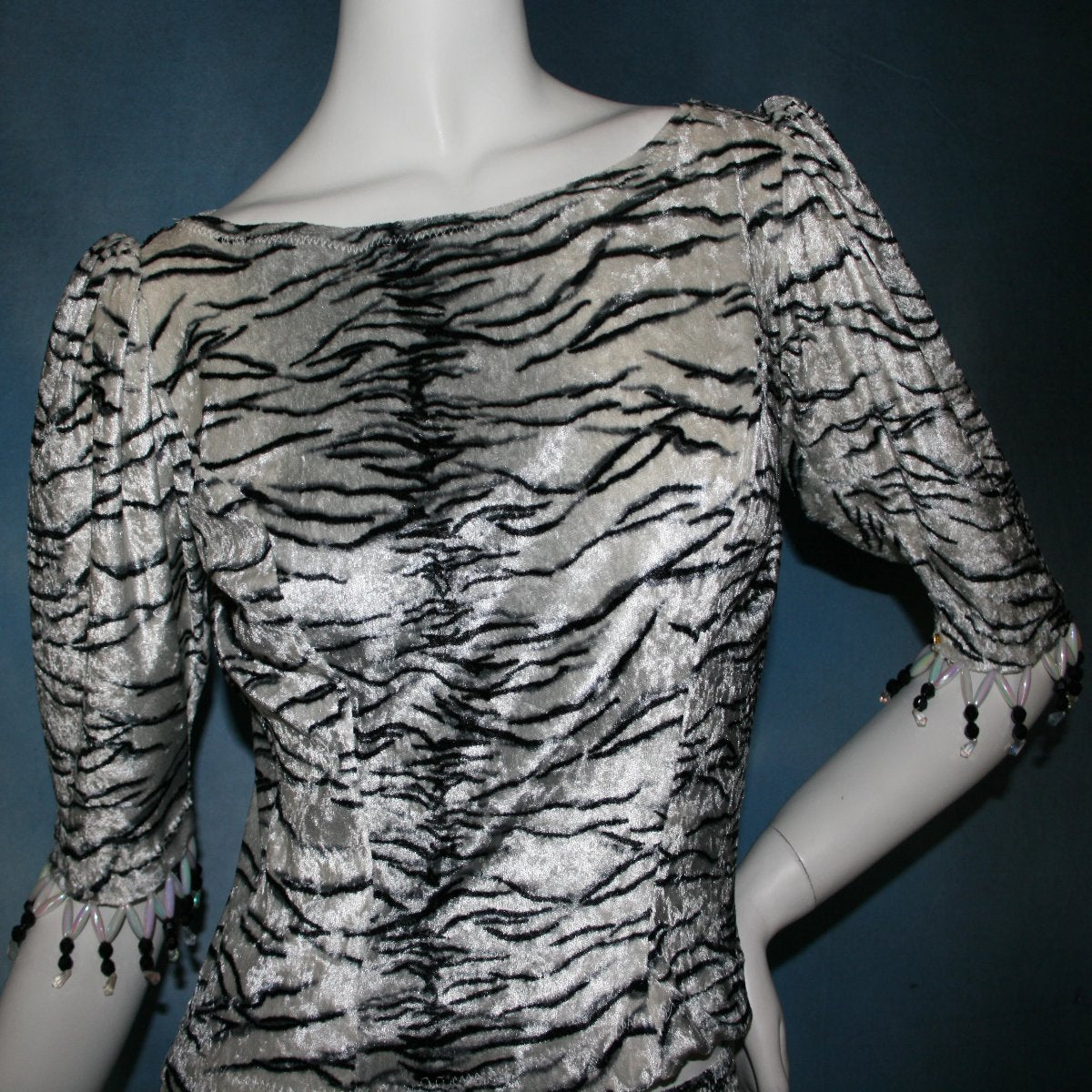 upper front view of Top & tulip style Latin/rhythm dance skirt created in white tiger print panne’ velvet with hand beading on sleeve edges of top. This is a fun & flirty Latin/rhythm dance set great for juniors as well!