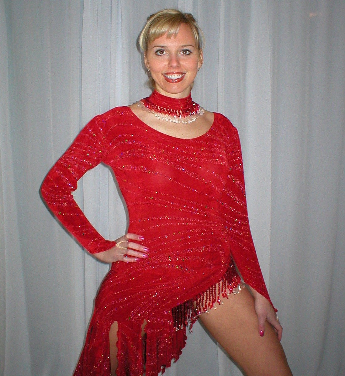 close up view of Red 3 piece ballroom converta dress consisting of a long sleeve red bodysuit, Latin-rhythm skirt with hand beading, smooth waltz length skirt plus neck piece with hand beading created out of deep red glitter slinky with a gorgeous wave pattern.