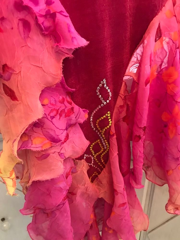 bottom details of Gorgeous rose colored converta ballroom dance dress was created on a nude illusion base of rose colored slinky with flounces of a gorgeous oriental flower print crinkle chiffon of pinks, yellows & oranges. Detailed Swarovski rhinestone work which ties in so beautifully with with the print chiffon, is done in pinks, yellows & orange.