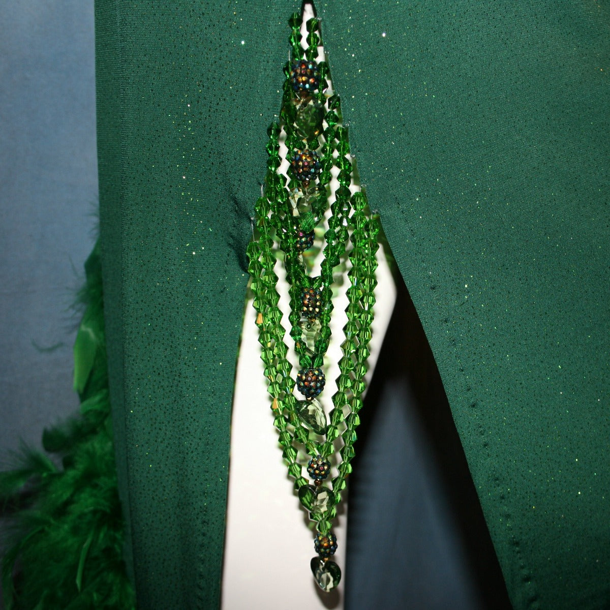 Crystal's Creations close up detail view of Green Latin/rhythm dress was created in luxurious deep emerald glitter slinky, embellished with chandelle feathers & Swarovski hand beaded detailing.