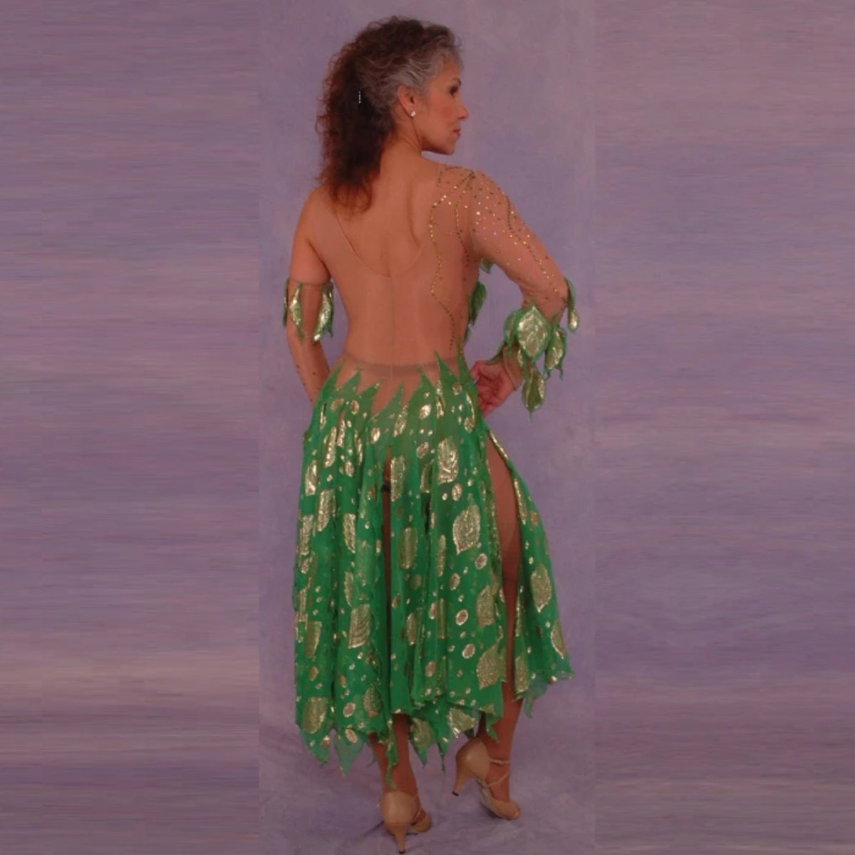 back view of Green Latin/rhythm dance dress was created on nude illusion base with green & gold metallic print chiffon… leaves hand cut & edged to embellish bodice, Swarovski rhinestones are trickled throughout in Vitrail medium(shines different shades of green & gold)