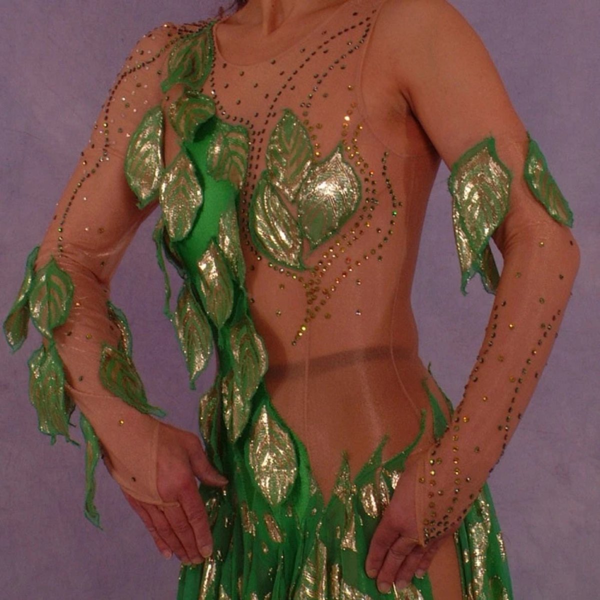 upper front view of Green Latin/rhythm dance dress was created on nude illusion base with green & gold metallic print chiffon… leaves hand cut & edged to embellish bodice, Swarovski rhinestones are trickled throughout in Vitrail medium(shines different shades of green & gold)
