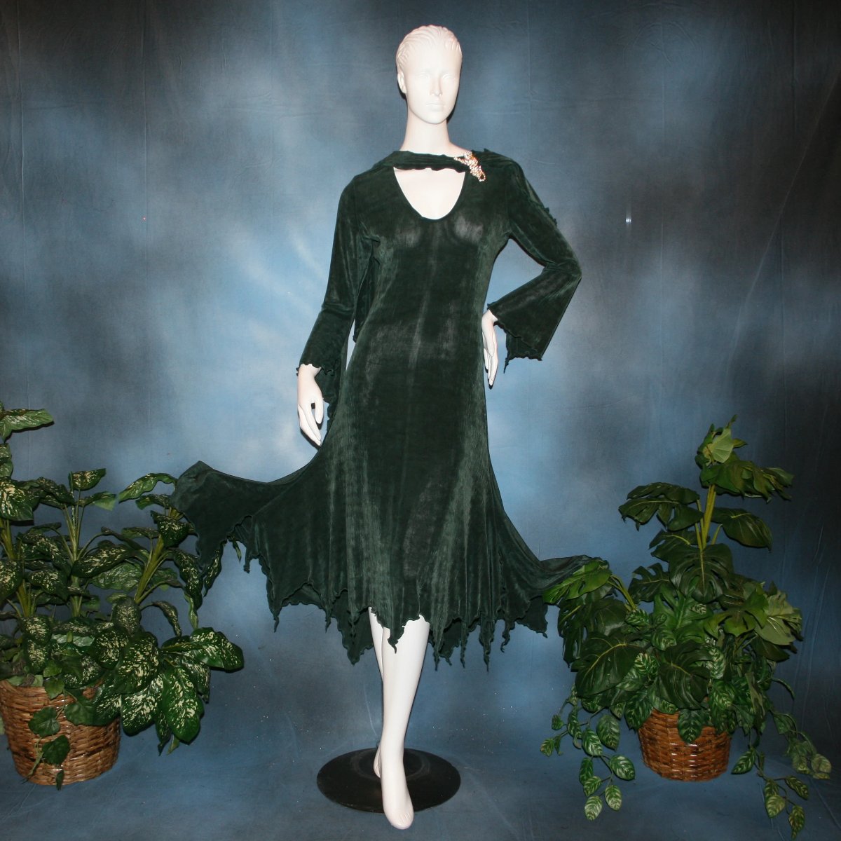Deep green social ballroom dress created in luxurious solid slinky fabric with attached draping on shoulders & peaked skirt edge. Very full around bottom..can be a beginner ballroom dancer smooth ballroom dress. Broach is not included. This ballroom social dress can be custom created in many colors.