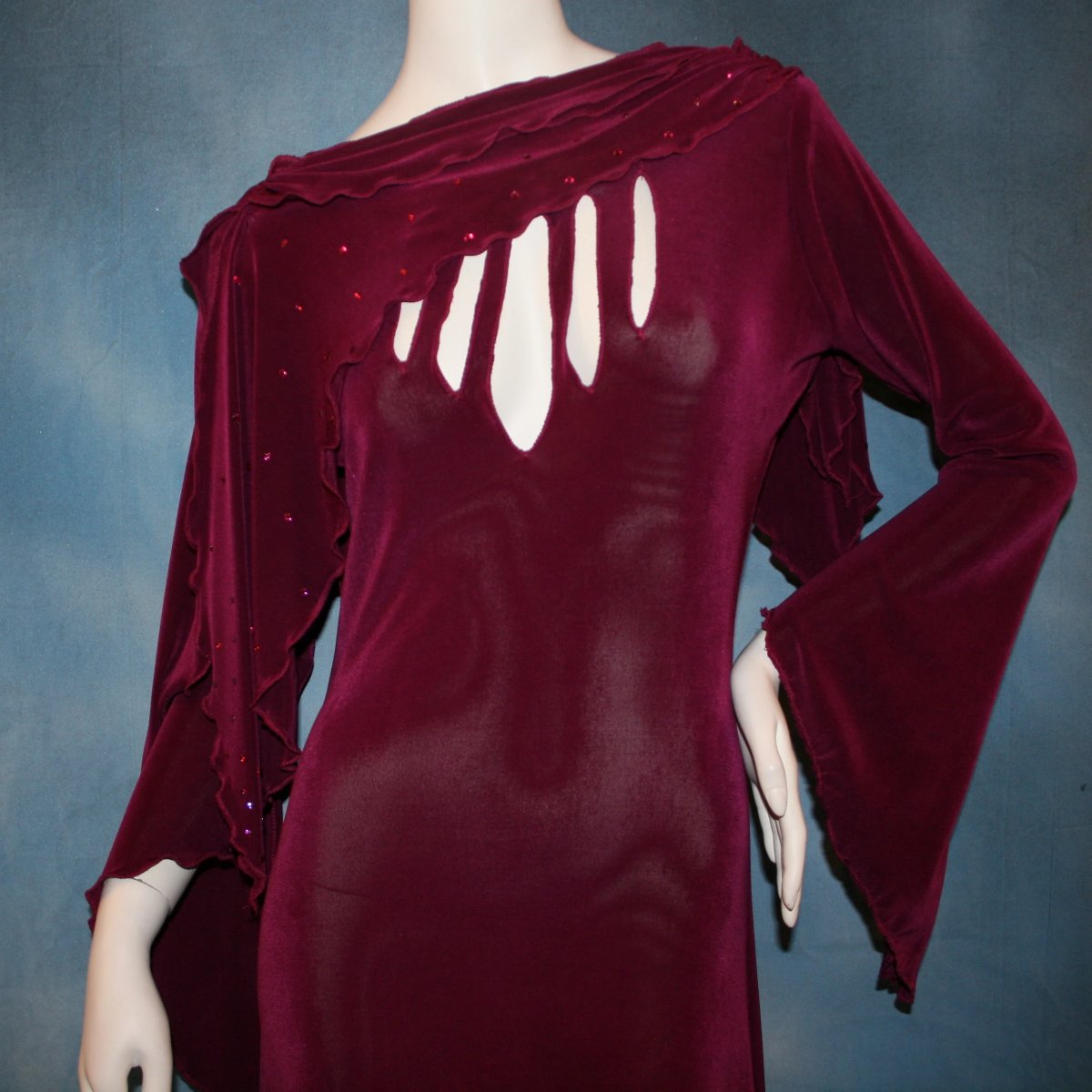close view of Magenta social ballroom dress created in luxurious solid slinky fabric with cutouts at bustline & attached double draping on shoulders, embellished with magenta Swarovski rhinestones, features a scalloped skirt edge. Very full around bottom & can be a beginner ballroom dancer smooth ballroom show or competition dress.