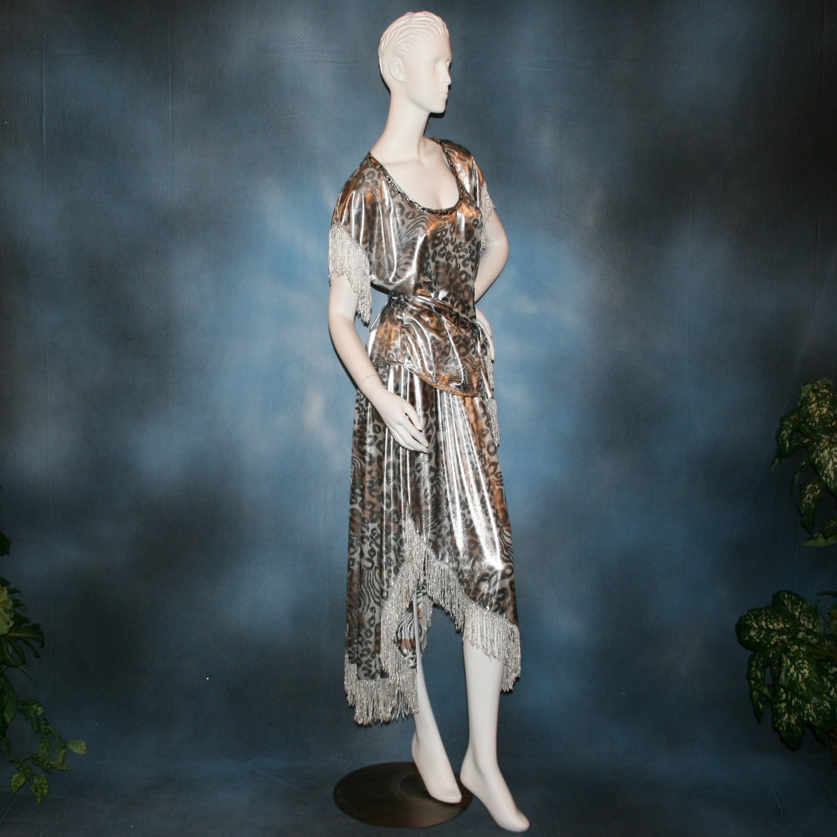 side view of Silver two panel Latin/rhythm skirt & top that has hand beading on neck edge of textured silver beads, with metallic fringe, was created of a leopard print knit with silver metallic on one side.