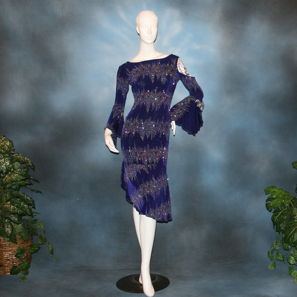 Deep royal purple Latin/rhythm/tango dress created in deep royal purple glitter slinky with an awesome electrifying glitter pattern features one longe sleeve, with flair at the bottom, & another very interesting cold shoulder detailed one with hand beading & a flaired flounce.