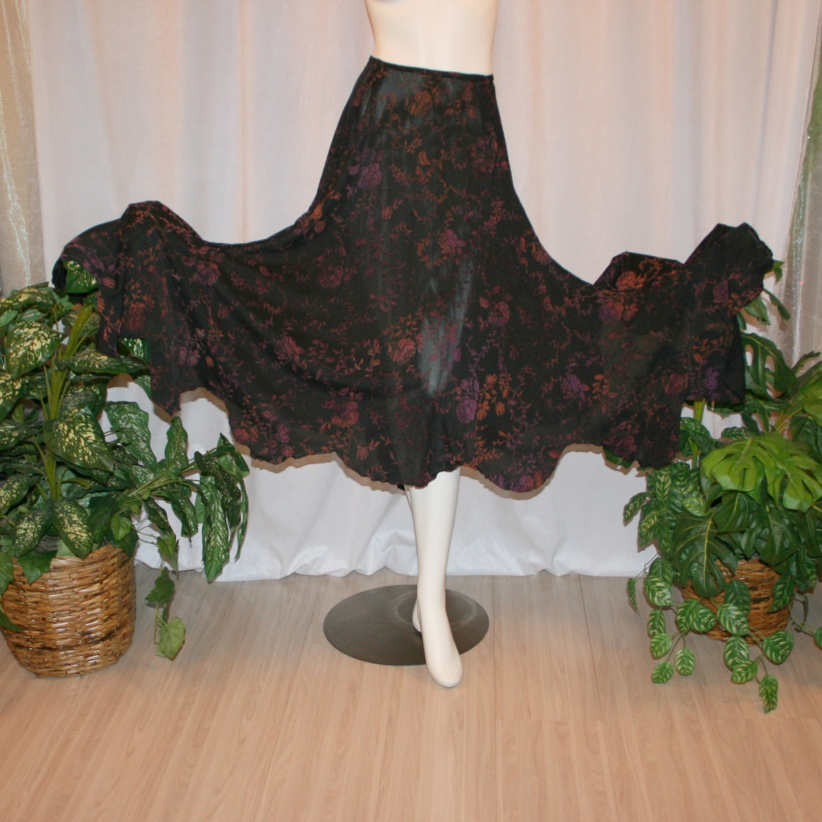 Flared view of Black velveteen ballroom skirt with a gorgeous floral pattern, it creates a delightful swirl of autumn colors with its gored seaming and abundant fullness, and elasticized waist for ease of fit. Deep scalloped hemline adds a touch of charm, perfect for any ballroom event, studio dance parties, practice, or teaching!