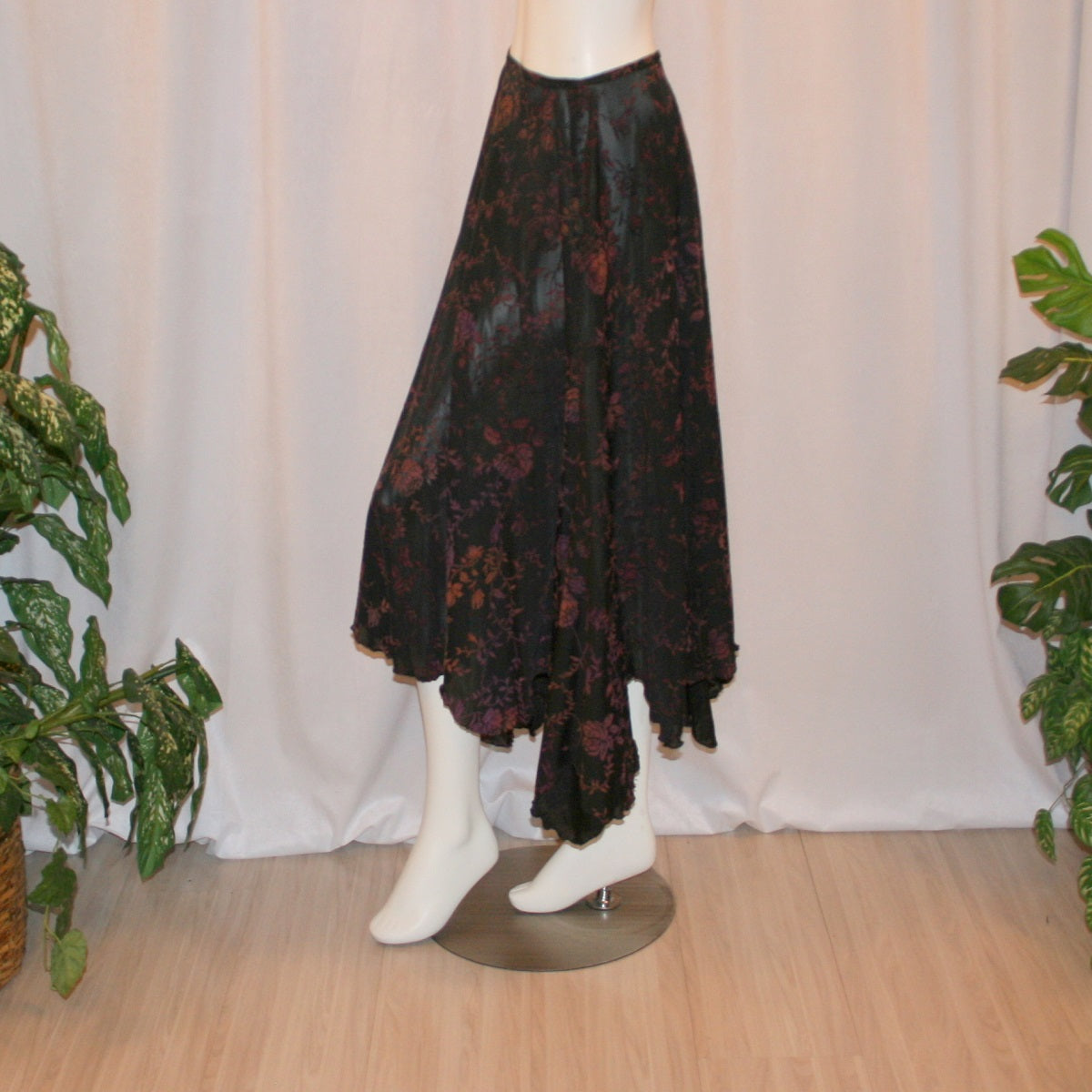 left side view of Black velveteen ballroom skirt with a gorgeous floral pattern, it creates a delightful swirl of autumn colors with its gored seaming and abundant fullness, and elasticized waist for ease of fit. Deep scalloped hemline adds a touch of charm, perfect for any ballroom event, studio dance parties, practice, or teaching!