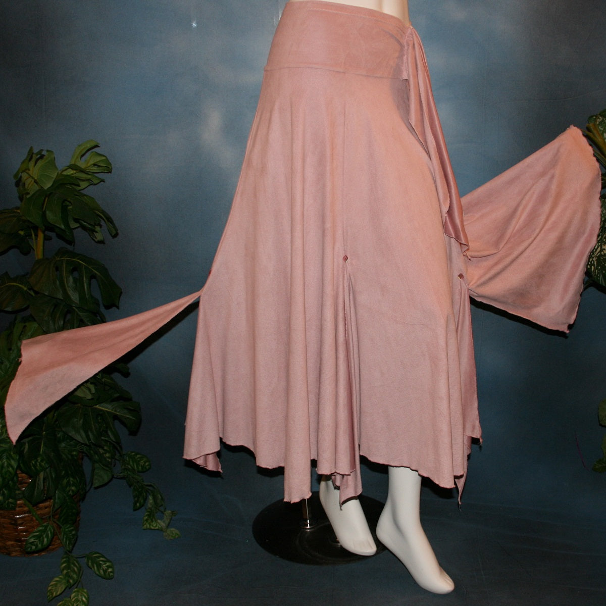 flared view of Lovely light rose dance skirt created of slightly stretchable suede cloth featuring a wide waist sash that flares out to several panels, with slits that have smaller floating panels with a rose colored acrylic gem at each.