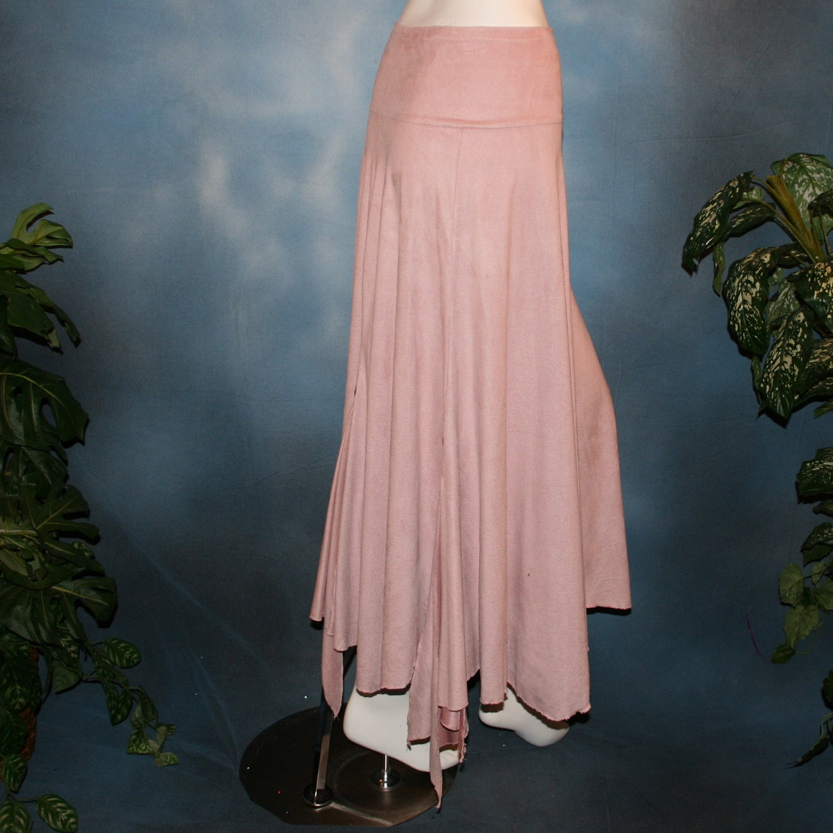 side view of Lovely light rose dance skirt created of slightly stretchable suede cloth featuring a wide waist sash that flares out to several panels, with slits that have smaller floating panels with a rose colored acrylic gem at each.