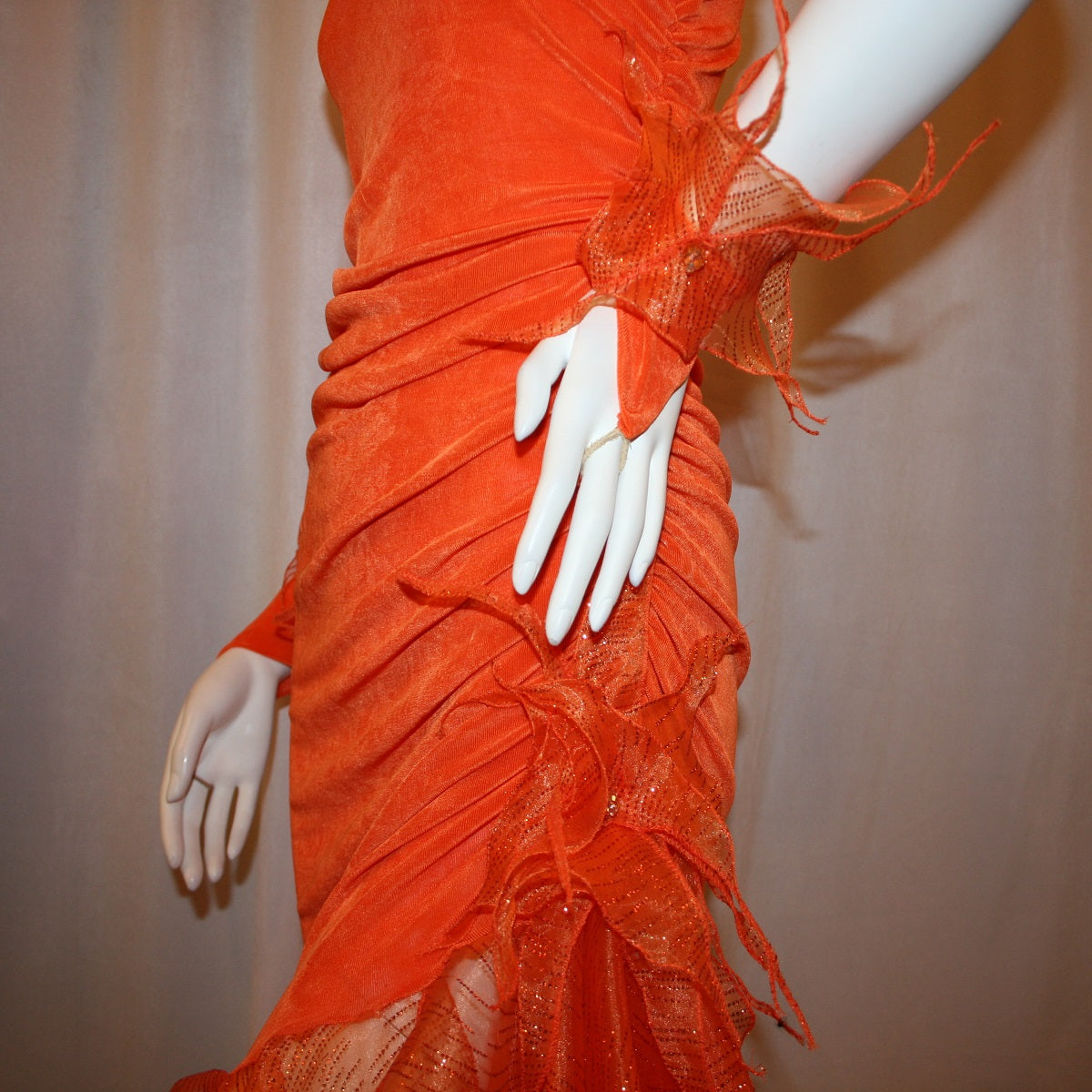 Crystal's Creations close up left side view of Orange Latin/rhythm dress was created in luxurious orange solid slinky with oodles of glitter organza flounces & accents, embellished with a touch of Swarovski hand beading.