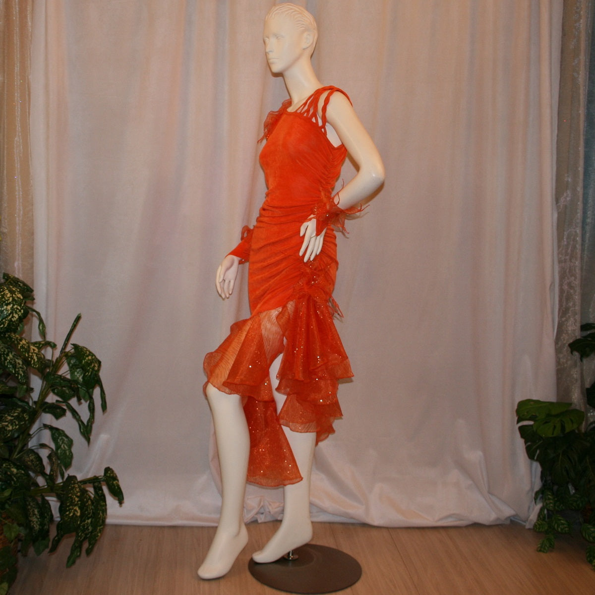 Crystal's Creations left side view of Orange Latin/rhythm dress was created in luxurious orange solid slinky with oodles of glitter organza flounces & accents, embellished with a touch of Swarovski hand beading.