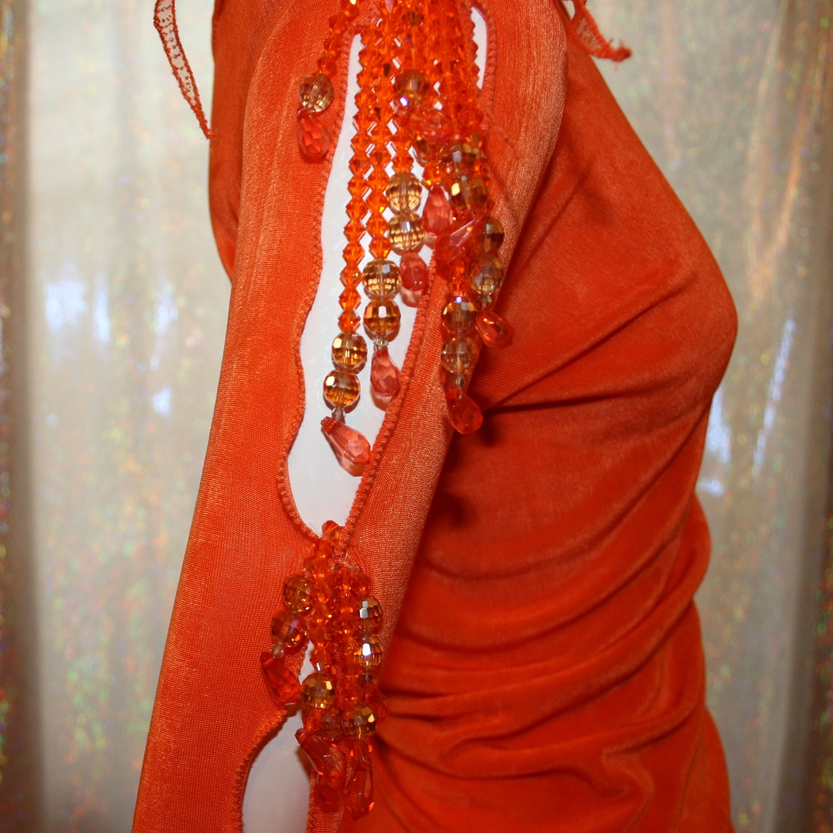 Crystal's Creations close up view of Orange Latin/rhythm dress was created in luxurious orange solid slinky with oodles of glitter organza flounces & accents, embellished with a touch of Swarovski hand beading.