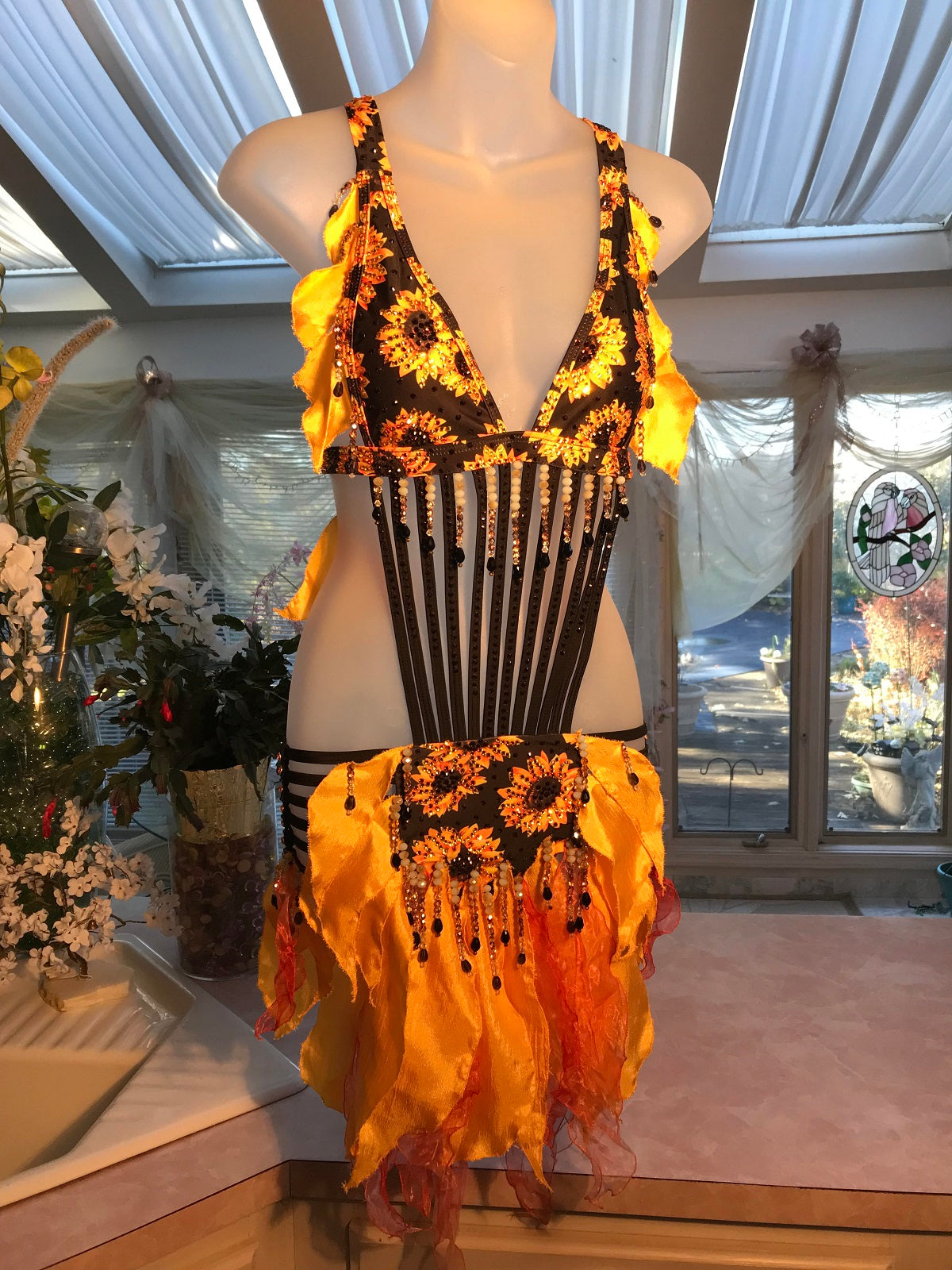 sunflower print Latin-rhythm dress created from a very strappy detailed bathing suit which I added hand crafted petal shape flounces in sunflower yellow satin & orange variegated organza, with extensive Swarovski hand beading in orange, pearlescent, gold & black faceted beads in round & tear drop shapes along with Swarovski rhinestone work throughout in yellow, orange & bronze.