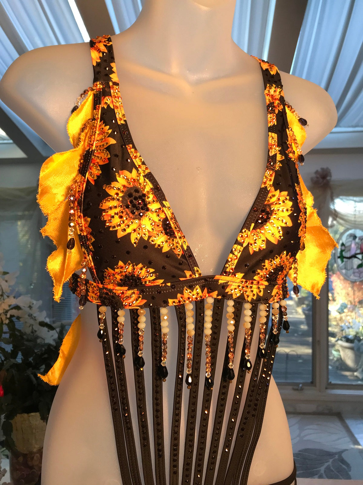 Top view of sunflower print Latin-rhythm dress created from a very strappy detailed bathing suit which I added hand crafted petal shape flounces in sunflower yellow satin & orange variegated organza, with extensive Swarovski hand beading in orange, pearlescent, gold & black faceted beads in round & tear drop shapes along with Swarovski rhinestone work throughout in yellow, orange & bronze.