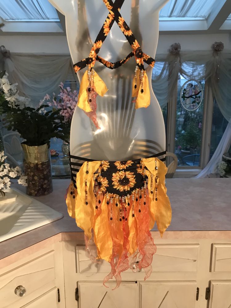 Back view of sunflower print Latin-rhythm dress created from a very strappy detailed bathing suit which I added hand crafted petal shape flounces in sunflower yellow satin & orange variegated organza, with extensive Swarovski hand beading in orange, pearlescent, gold & black faceted beads in round & tear drop shapes along with Swarovski rhinestone work throughout in yellow, orange & bronze.