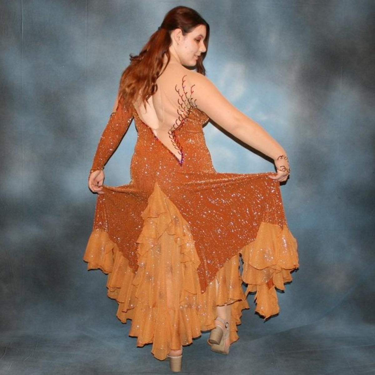 Crystal's Creations back view of Bronze ballroom dress created in bronze glitter slinky with a swirl/ripple design on nude illusion base with oodles of amber glitter chiffon flounces, is embellished with volcano Swarovski rhinestone work.