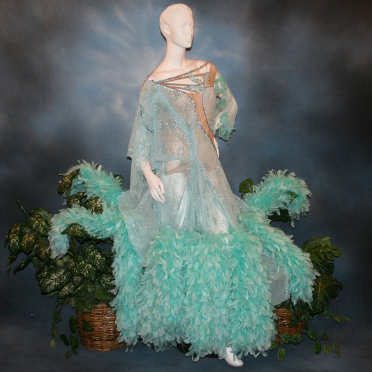 Crystal's Creations Aqua blue ballroom dress created in gorgeous aqua blue glitter sheer mesh overlaid on a nude illusion base has lots of gorgeous aqua chandelle feathers, embellished with aquamarine Swarovski rhinestone work. This ballroom dress also features delicate Swarovski embellished strap detailing.