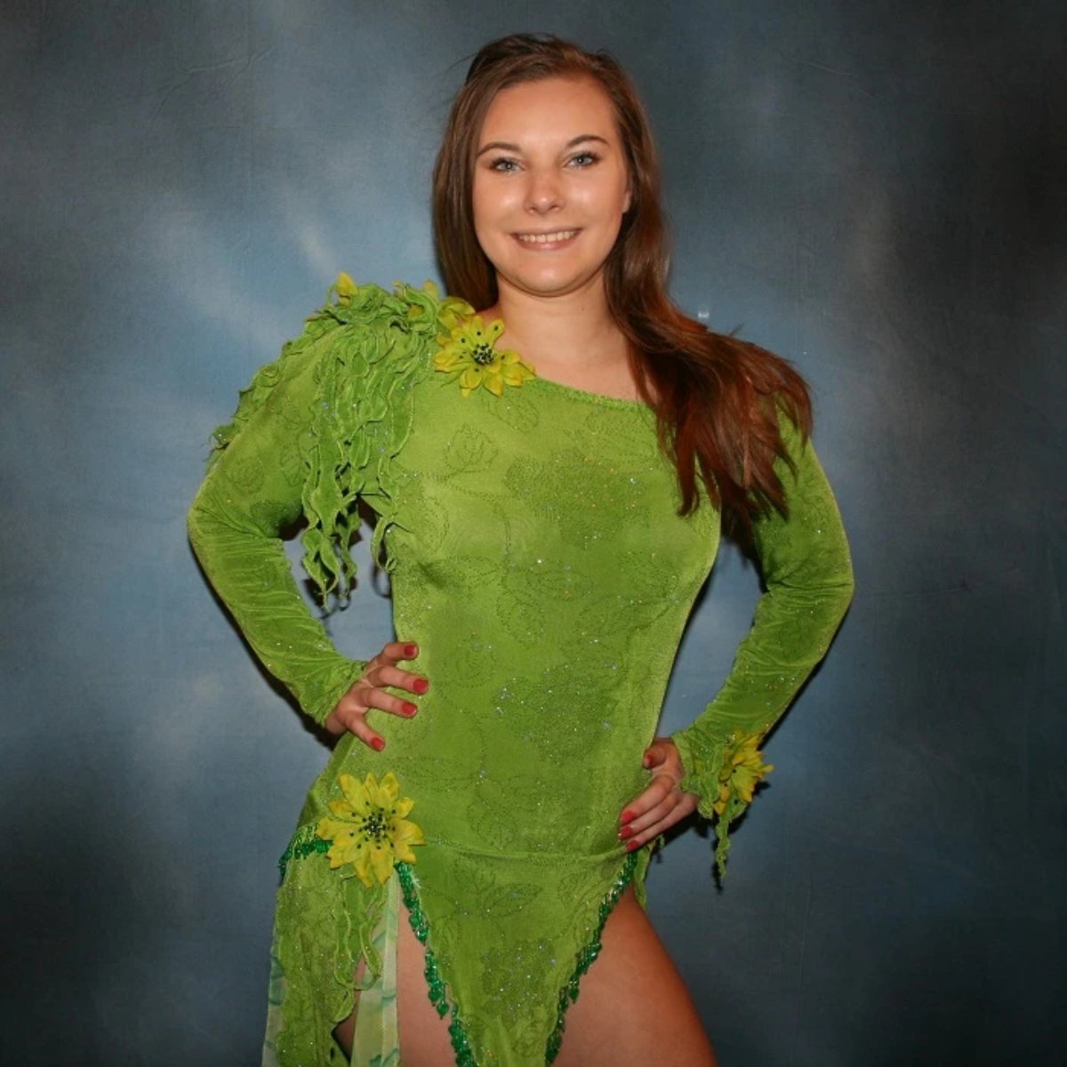 close upper view of Green Latin/rhythm dress created in apple green glitter slinky fabric, with print chiffon accents, embellishing done of silk flowers with Swarovski rhinestone work, also features back strap detailing along with extensive hand beading on skirt edges & choker.