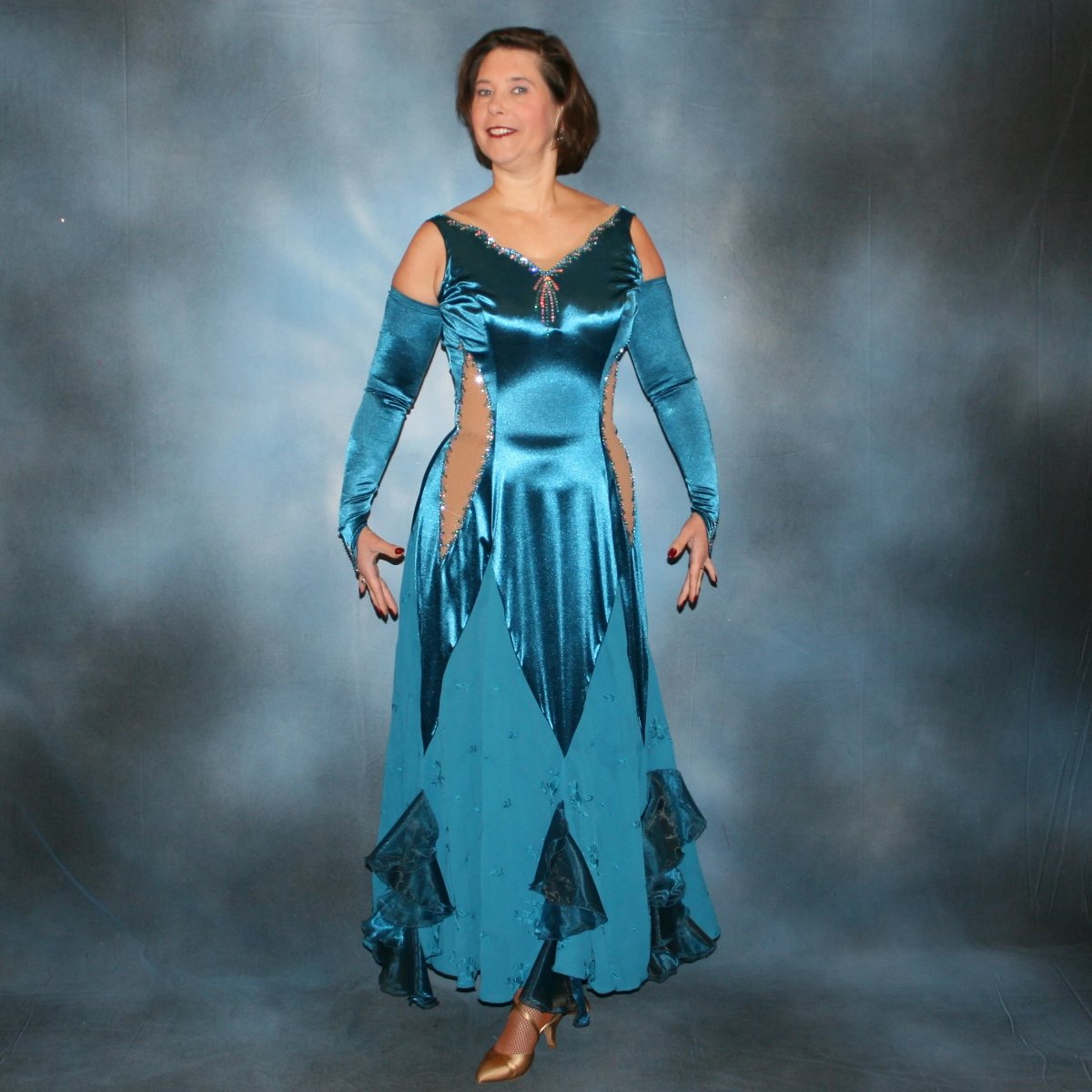 Crystal's Creations Blue ballroom dance dress was created in luxurious deep sea blue stretch satin with deep sea blue crepe chiffon embroidered insets, organza flounces…nude illusion cutout detailing…embellished with CAB & blue zircon Ab Swarovski stonework.