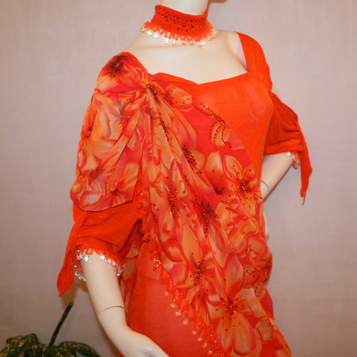 close view of Orange ballroom dress with 3/4 cold shoulder, billowy sleeves, created of luxurious orange solid slinky & yards of an orange tropical print textured chiffon. 