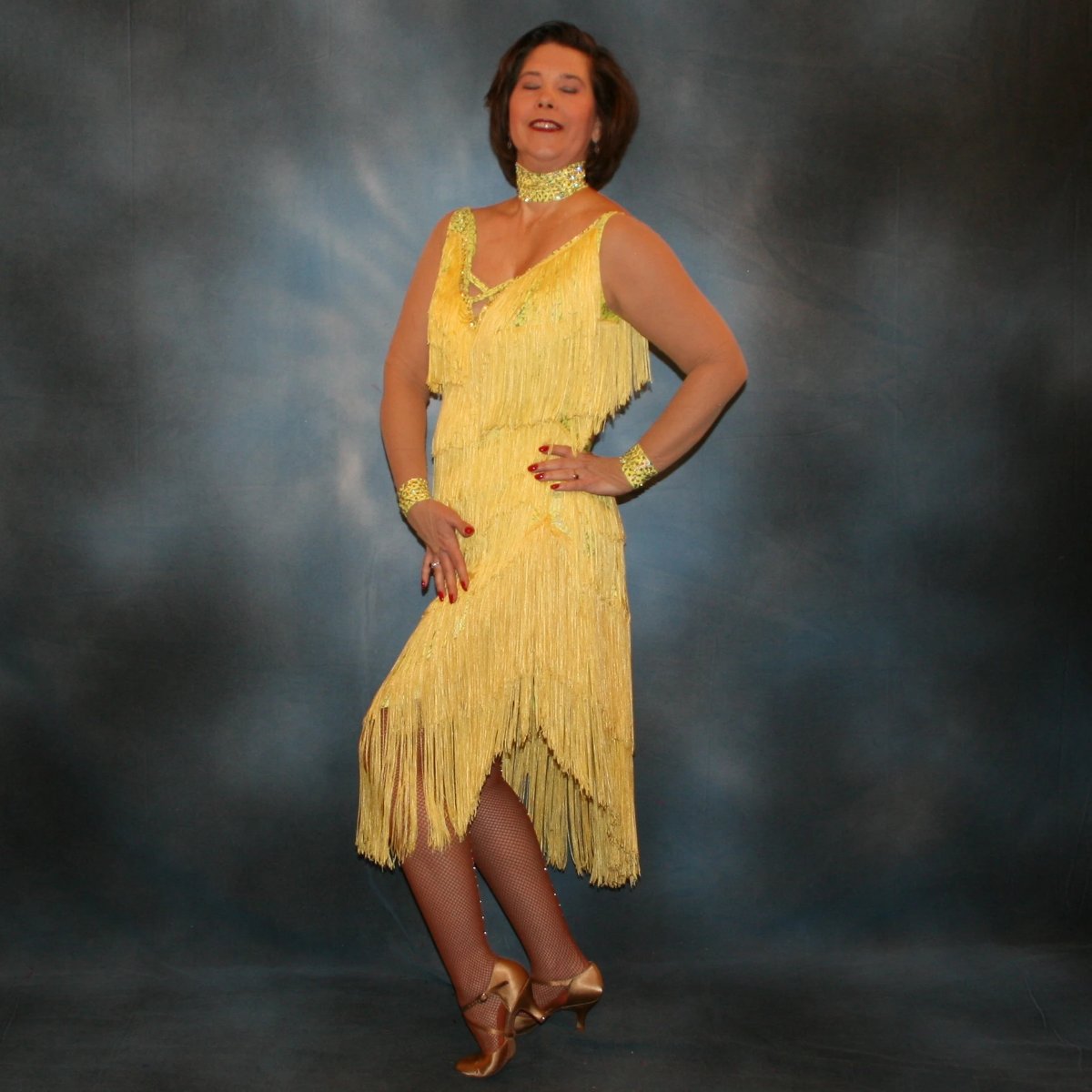 Crystal's Creations side view of Yellow Latin/rhythm fringe dress created in yellow splash metallic lycra with yards of chainette fringe, sheer nude illusion sleeves, embellished with jonquil Swarovski rhinestones.