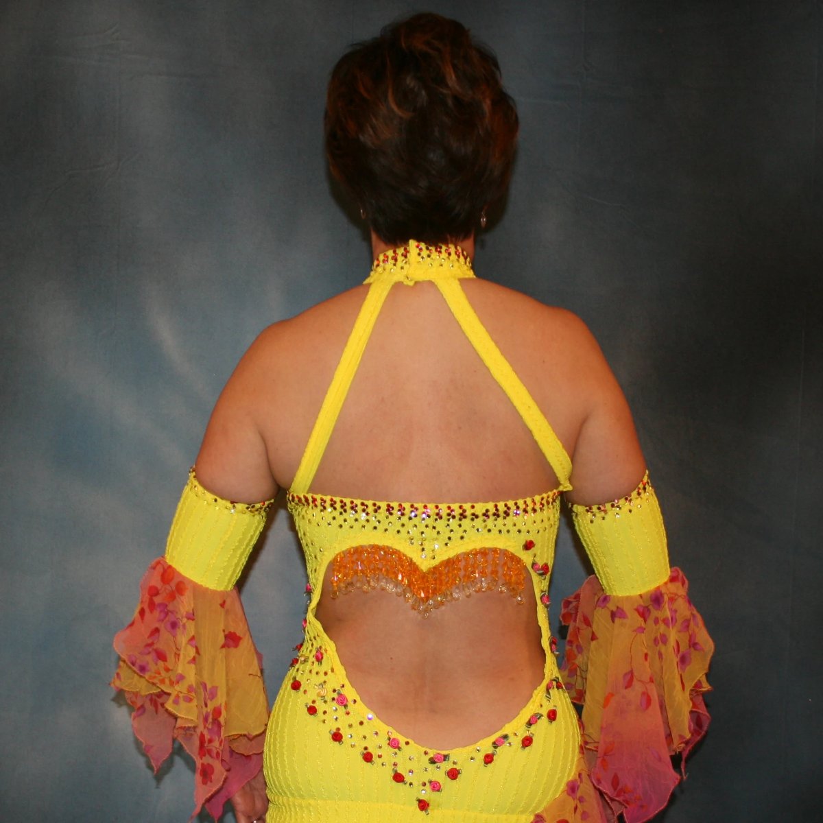 Crystal's Creations upper back view of Yellow Latin/rhythm dress created in textured lycra, features silk roses along with rose, jonquil(yellow) & hyacinth(orange) Swarovski rhinestones, and 2 rows of flounces of a gorgeous delicate oriental floral print chiffon. 