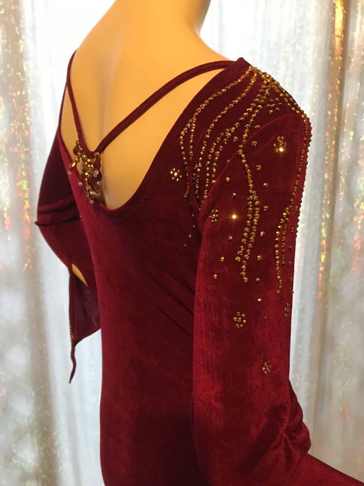 Crystal's Creations side shoulder view of Magenta Latin/rhythm/tango dress created out of deep magenta/wine slinky features ruching, long flared sleeves & is embellished with gold aurum Swarovski rhinestone work with a bit of Swarovski bead detail on back strap