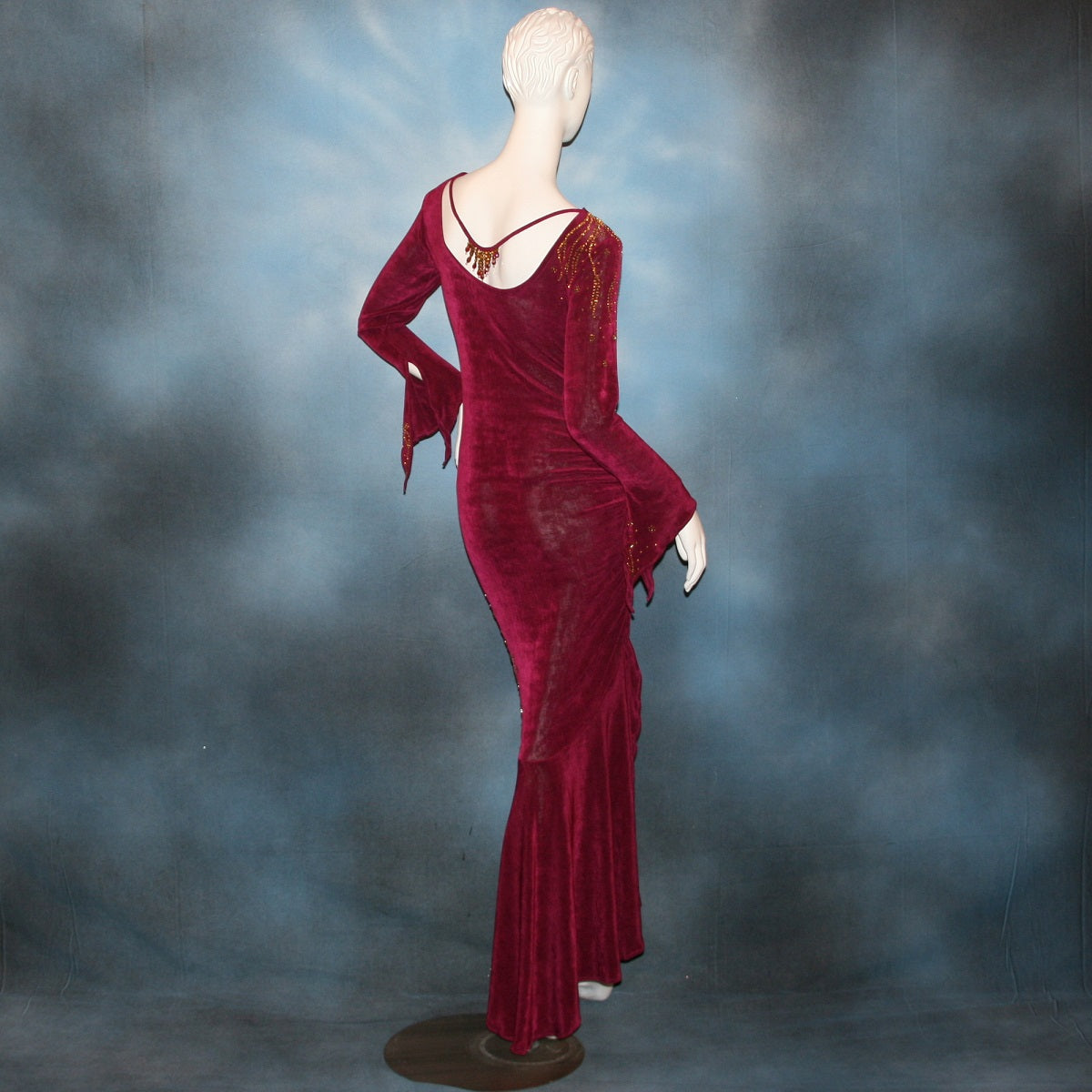 Crystal's Creations back view of Magenta Latin/rhythm/tango dress created out of deep magenta/wine slinky features ruching, long flared sleeves & is embellished with gold aurum Swarovski rhinestone work 