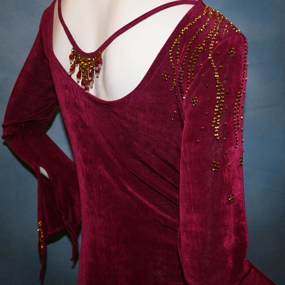 Crystal's Creations back close up view of Magenta Latin/rhythm/tango dress created out of deep magenta/wine slinky features ruching, long flared sleeves & is embellished with gold aurum Swarovski rhinestone work