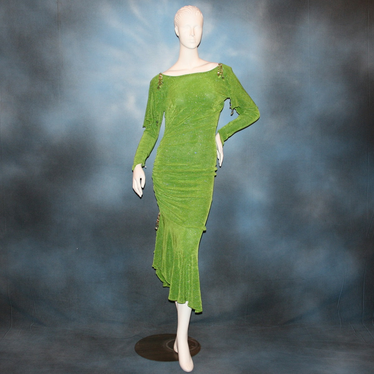 Apple green social Latin/rhythm dress was created of apple green glitter slinky, features ruching on the right side, long sleeves, scoop back, & full skirting with open side that has Swarovski hand beaded detail