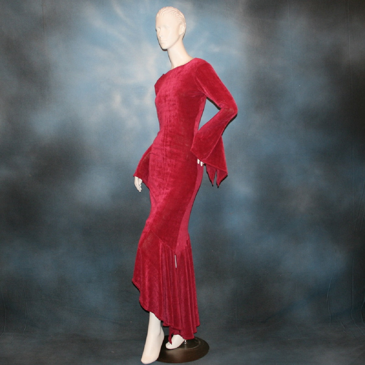 left side view of Deep rose Latin/rhythm/social dress created of luxurious deep rose slinky features ruching up the right side & long sleeves with an open flared detail.