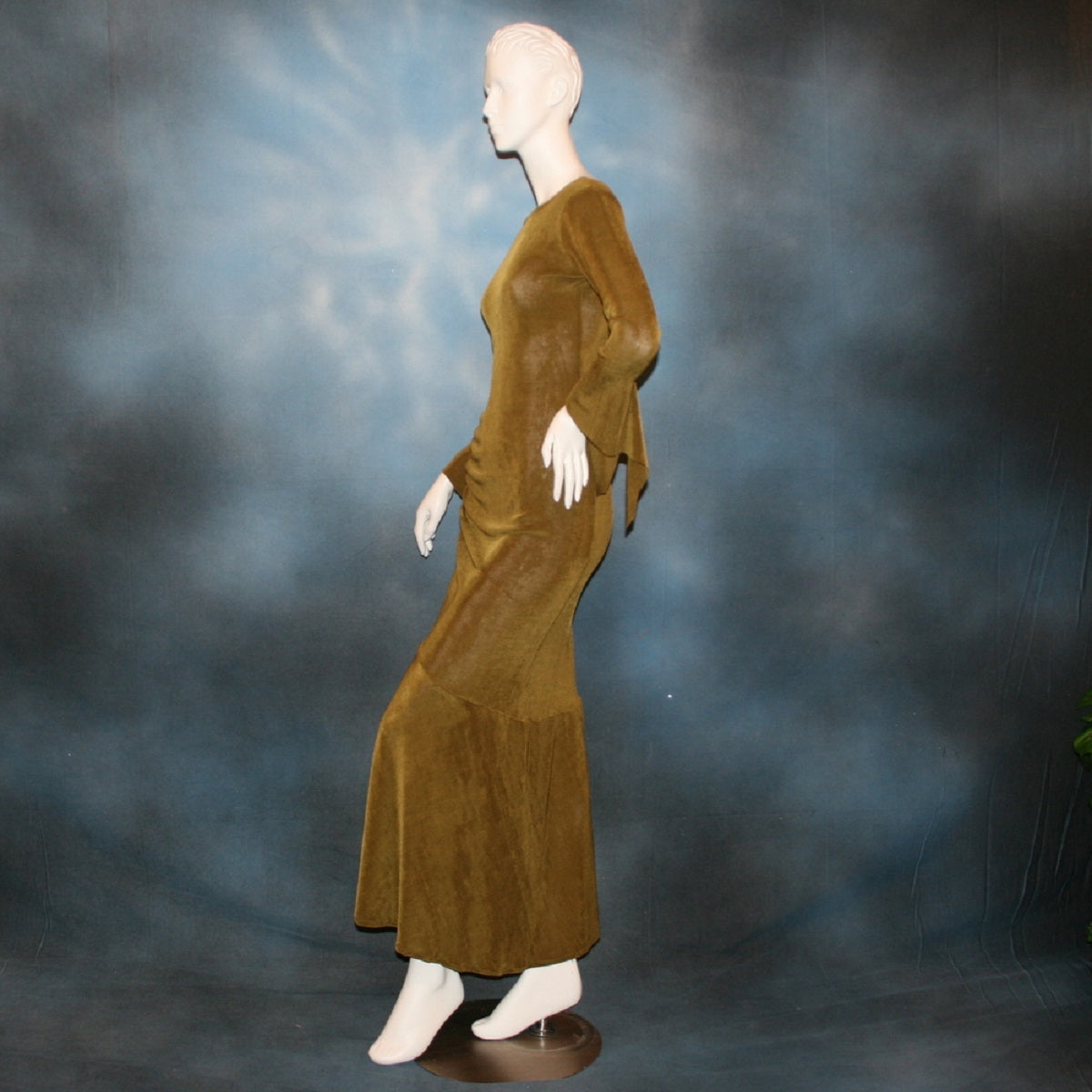 left side view of Sage green Latin/rhythm/social dress created of luxurious sage green slinky features ruching up the right side & long sleeves with an open flared detail.
