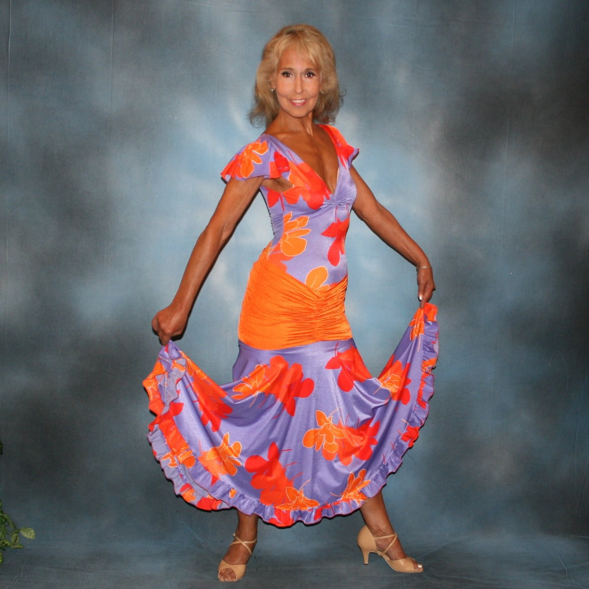 ropical print social ballroom dress created in lycra of deep orchid tropical print with purple flowers, features ruffly cap sleeves & ruffle on full circle skirt. The bodysuit is built right into the dress, so it makes a great & fun dress for teaching, especially if you work on theater arts! The look is finished with an orange ruched hip sash.